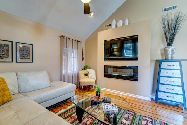 living room featuring vaulted ceiling, wood finished floors, visible vents, and ceiling fan