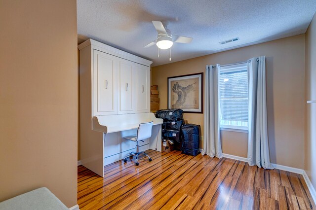 office featuring visible vents, a textured ceiling, baseboards, and light wood-style floors