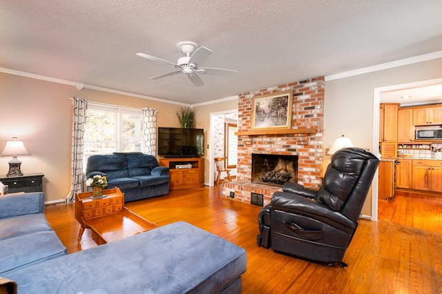 living area featuring a fireplace, light wood-style floors, a ceiling fan, and crown molding