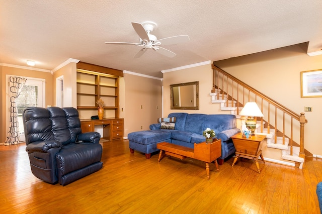 living area featuring a ceiling fan, a textured ceiling, wood finished floors, stairway, and crown molding