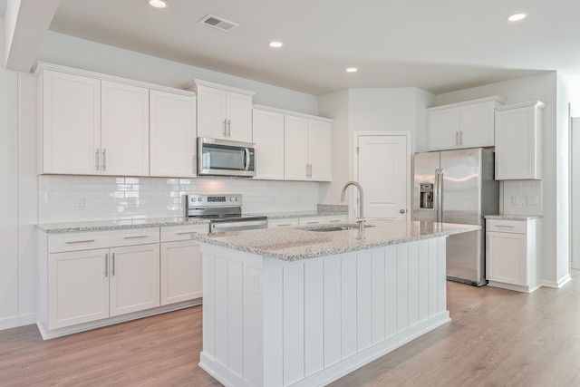 kitchen featuring stainless steel appliances, white cabinetry, sink, and light hardwood / wood-style floors