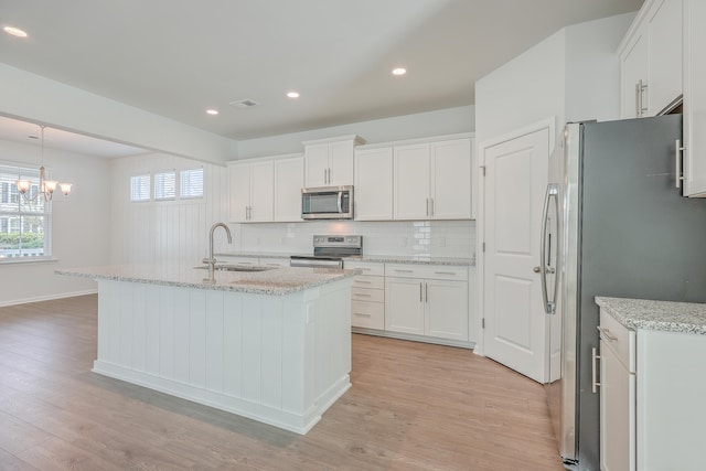 kitchen featuring white cabinetry, appliances with stainless steel finishes, and an island with sink