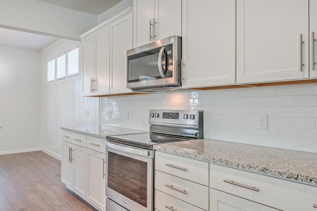 kitchen featuring white cabinetry, stainless steel appliances, light stone counters, and tasteful backsplash