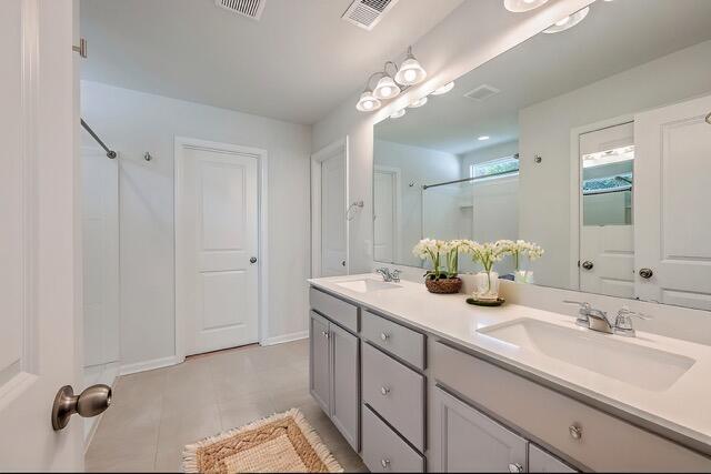 bathroom with tile patterned floors, vanity, and a shower with door