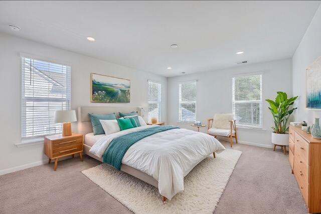 bedroom with multiple windows and light colored carpet