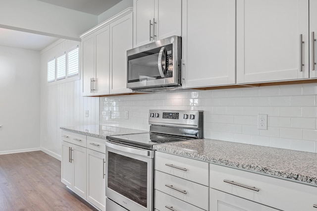 kitchen featuring light stone counters, decorative backsplash, stainless steel appliances, and white cabinets