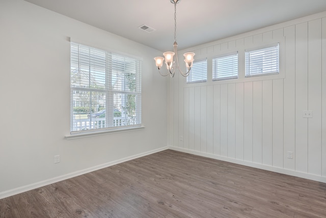 spare room featuring hardwood / wood-style flooring, a wealth of natural light, and a notable chandelier