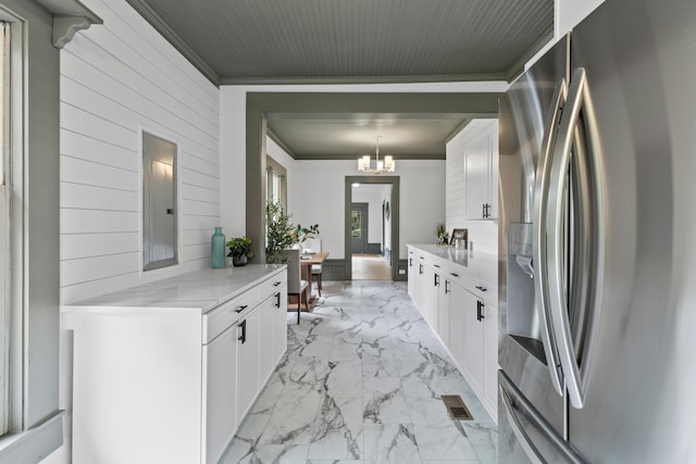 285 Roosevelt Dr, Saint Stephen, SC 29479 - kitchen with stainless steel refrigerator with ice dispenser, light marble finish floors, wooden walls, a chandelier, and white cabinets