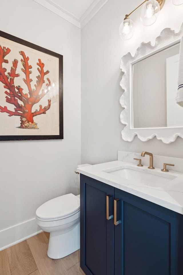 bathroom featuring toilet, vanity, wood-type flooring, and crown molding