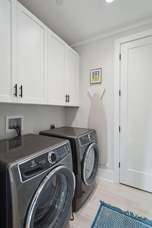 laundry room with cabinets, separate washer and dryer, crown molding, and light hardwood / wood-style flooring