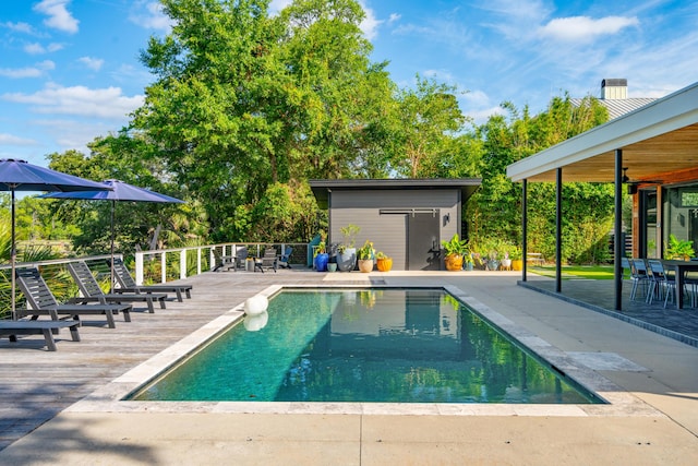 view of swimming pool featuring a wooden deck, ceiling fan, and a shed