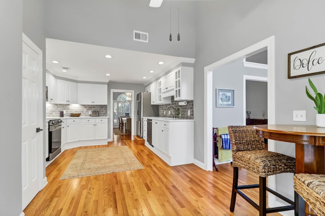 2707 Waterpointe Cir, Mount Pleasant, SC 29466 - kitchen featuring appliances with stainless steel finishes, light wood finished floors, light countertops, backsplash, and white cabinetry