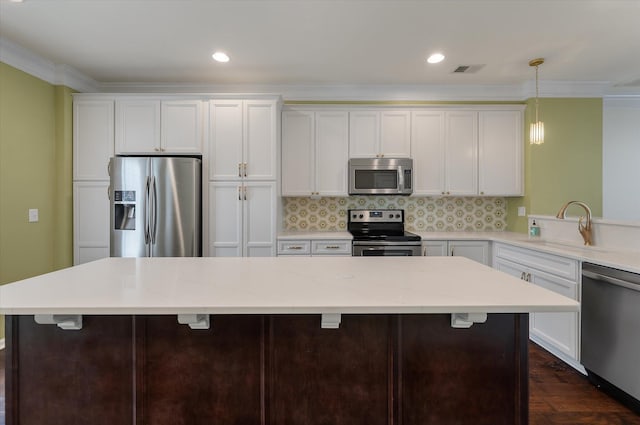 1533 Bluewater Way, Charleston, SC 29414 - kitchen with stainless steel appliances, a sink, ornamental molding, white cabinetry, and a center island