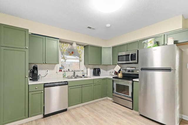 7696 Brandywine Rd, North Charleston, SC 29420 - kitchen featuring appliances with stainless steel finishes, green cabinets, light countertops, light wood-type flooring, and decorative backsplash
