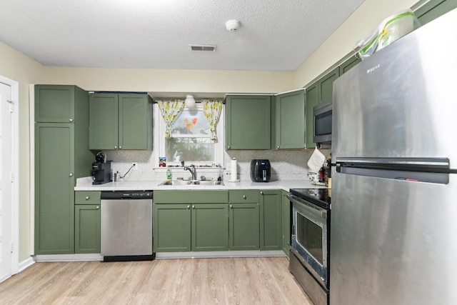7696 Brandywine Rd, North Charleston, SC 29420 - kitchen featuring stainless steel appliances, green cabinetry, light countertops, light wood-style floors, and backsplash