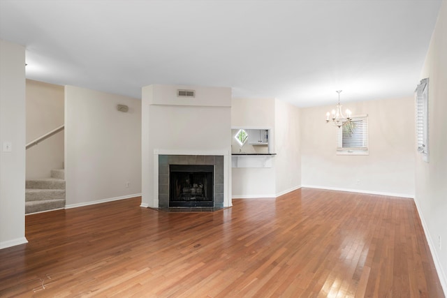 22 Ogier St, Charleston, SC 29403 - unfurnished living room featuring a chandelier, stairs, hardwood / wood-style floors, and a tiled fireplace