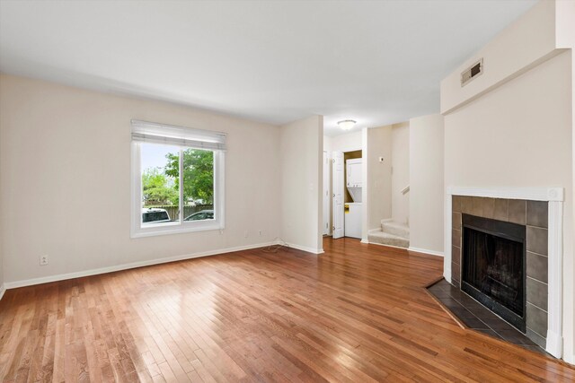 22 Ogier St, Charleston, SC 29403 - unfurnished living room with wood finished floors, a tile fireplace, and stairway