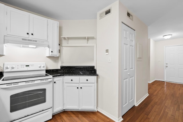 22 Ogier St, Charleston, SC 29403 - kitchen with white electric stove, under cabinet range hood, hardwood / wood-style floors, white cabinetry, and dark stone countertops