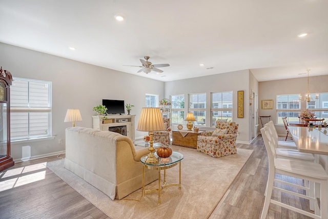 living room featuring light hardwood / wood-style flooring and ceiling fan with notable chandelier