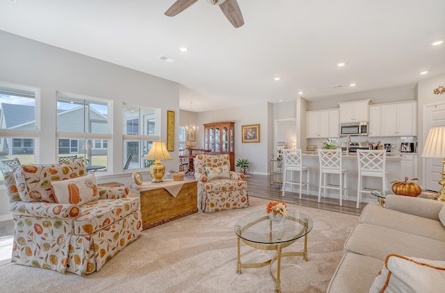 living room featuring a wealth of natural light, light hardwood / wood-style flooring, and ceiling fan with notable chandelier