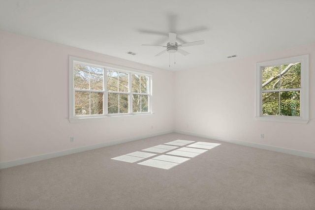 unfurnished room with a healthy amount of sunlight, carpet, visible vents, and baseboards