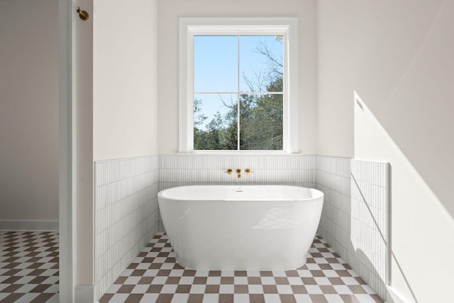 full bath featuring a freestanding bath, wainscoting, tile walls, and tile patterned floors