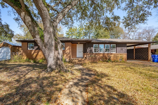 view of front facade featuring brick siding, an attached carport, and a front lawn