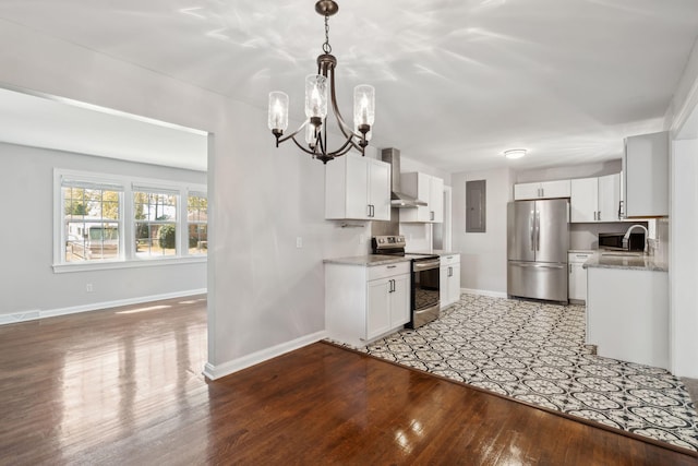 kitchen featuring wall chimney range hood, a chandelier, appliances with stainless steel finishes, light wood-style floors, and white cabinetry