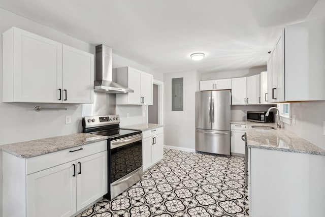 kitchen with wall chimney range hood, electric panel, appliances with stainless steel finishes, white cabinets, and a sink