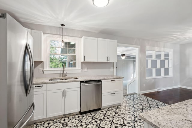 kitchen featuring a ceiling fan, a sink, appliances with stainless steel finishes, white cabinets, and baseboards