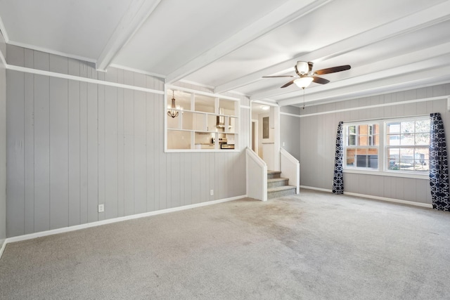 carpeted spare room with beamed ceiling, ceiling fan with notable chandelier, baseboards, and stairway