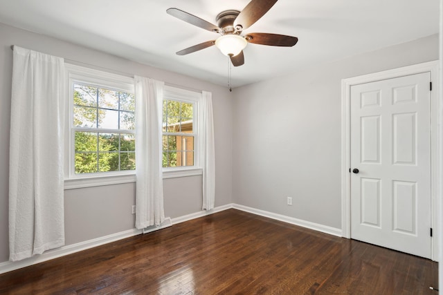 spare room featuring a ceiling fan, dark wood-style flooring, and baseboards