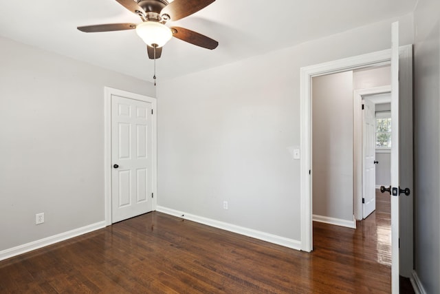 empty room featuring baseboards, dark wood finished floors, and a ceiling fan