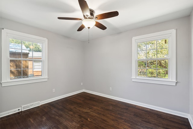 spare room featuring dark wood finished floors, visible vents, plenty of natural light, and baseboards