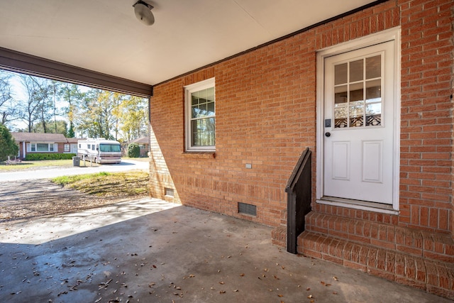 property entrance with crawl space, brick siding, and visible vents