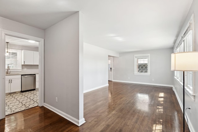 unfurnished living room with wood finished floors, baseboards, and a sink