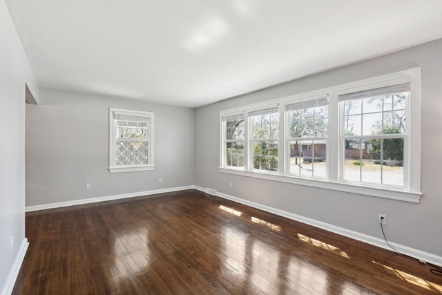 unfurnished room featuring dark wood-style floors and baseboards