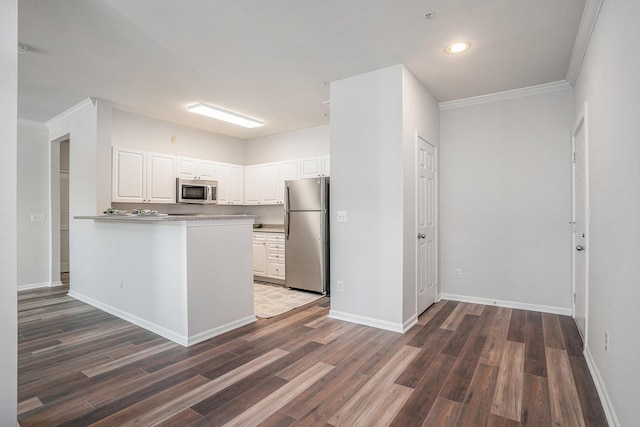 kitchen with white cabinetry, dark hardwood / wood-style floors, kitchen peninsula, appliances with stainless steel finishes, and ornamental molding