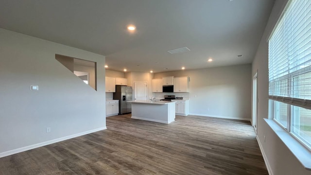 kitchen featuring white cabinetry, dark hardwood / wood-style flooring, a center island with sink, and appliances with stainless steel finishes