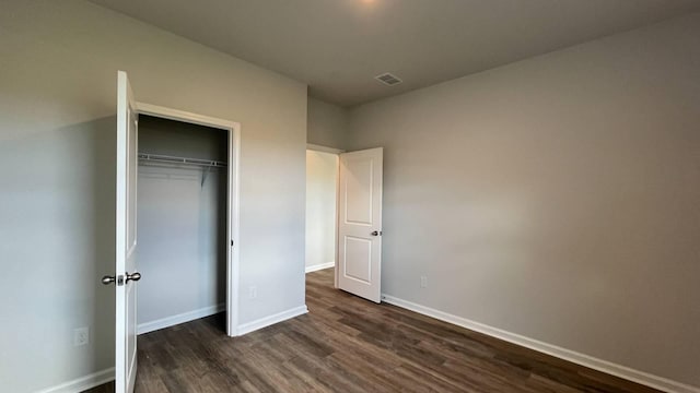 unfurnished bedroom featuring dark wood-type flooring and a closet