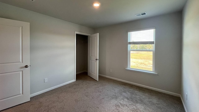 unfurnished bedroom with light colored carpet and a closet