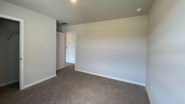 unfurnished bedroom with a closet and dark colored carpet