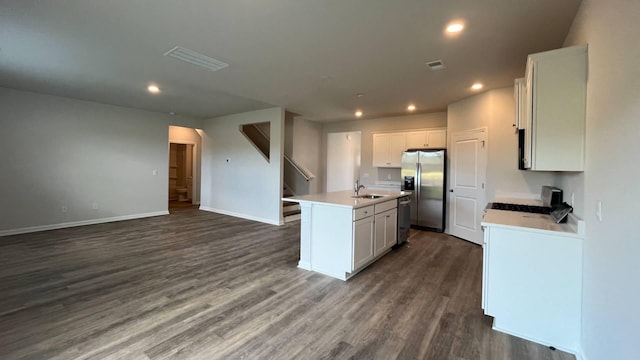 kitchen with white cabinetry, appliances with stainless steel finishes, dark hardwood / wood-style flooring, and an island with sink