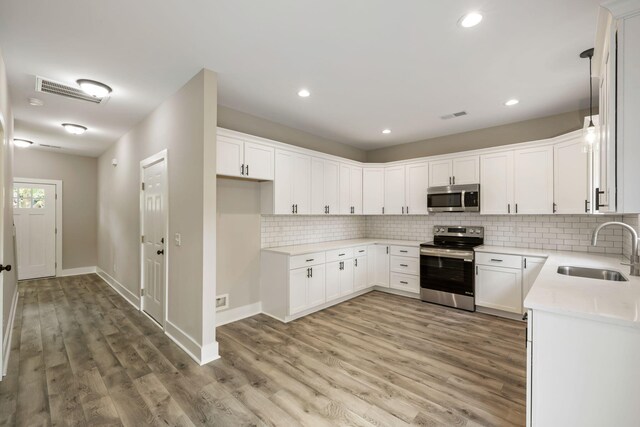 2960 Blackfish Rd, Johns Island, SC 29455 - kitchen featuring appliances with stainless steel finishes, a sink, light wood-style flooring, decorative backsplash, and light countertops