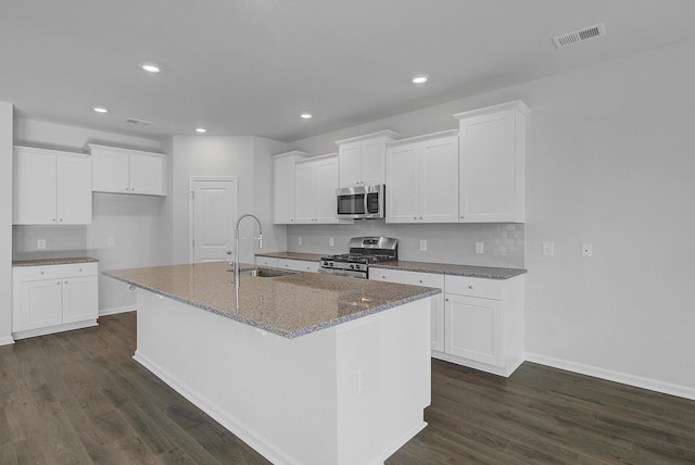 kitchen featuring appliances with stainless steel finishes, a sink, an island with sink, baseboards, and recessed lighting