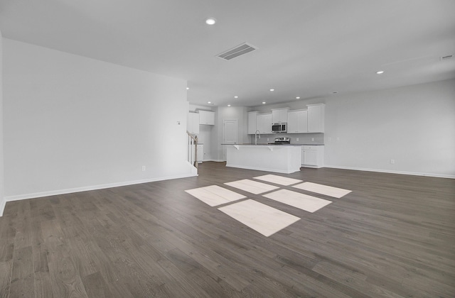 unfurnished living room with a sink, recessed lighting, dark wood-style flooring, and baseboards
