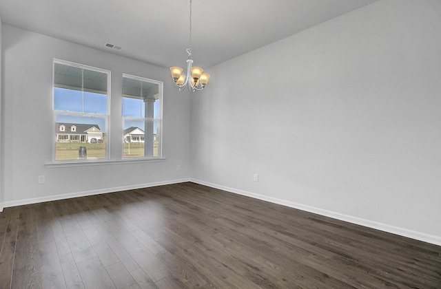 empty room with a chandelier, dark wood-type flooring, and baseboards