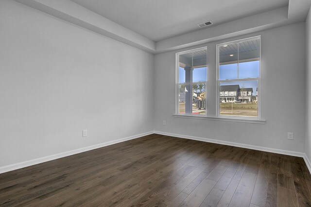 spare room featuring baseboards and dark wood-style floors