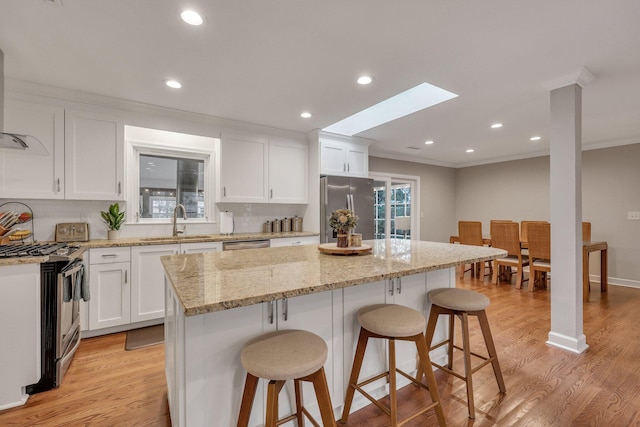 kitchen featuring a kitchen island, white cabinetry, appliances with stainless steel finishes, and sink