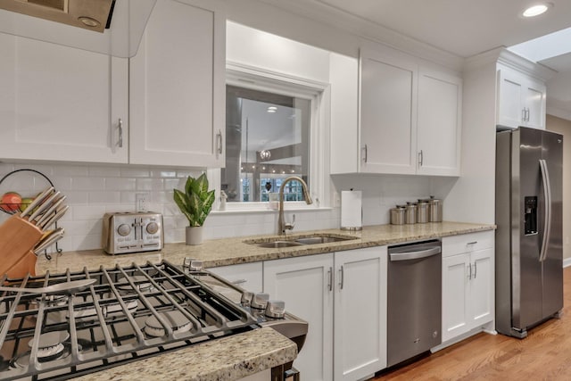 kitchen featuring sink, appliances with stainless steel finishes, white cabinetry, tasteful backsplash, and light stone countertops